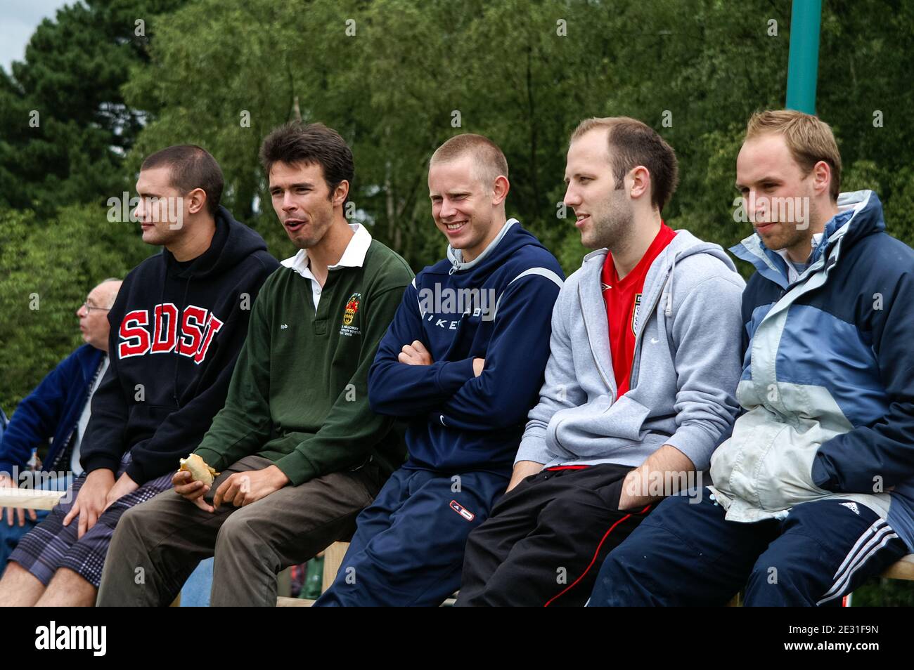 Un groupe de jeunes hommes assis sur un banc à regarder quelque chose, probablement un événement sportif, Royaume-Uni Banque D'Images