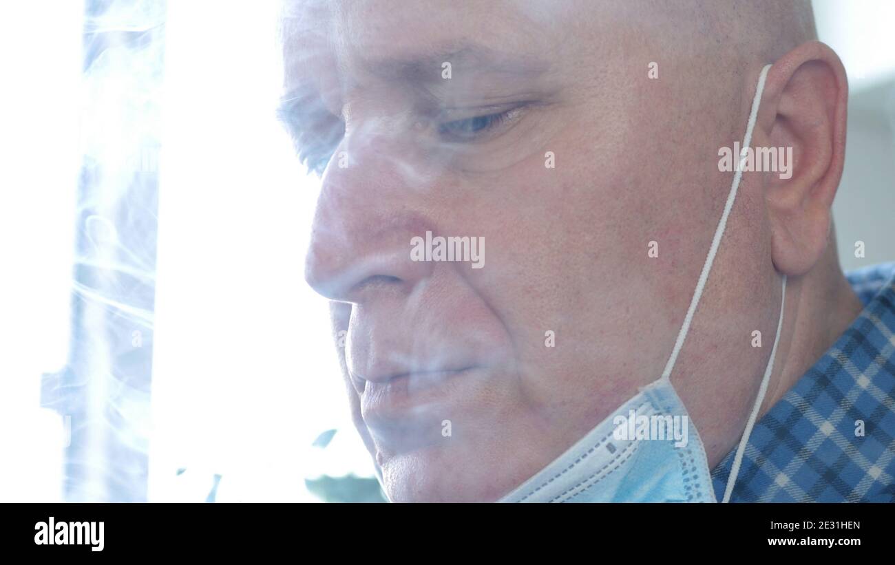 Image avec un homme qui fume une cigarette en utilisant on Le visage un masque de protection contre l'infection virale Banque D'Images