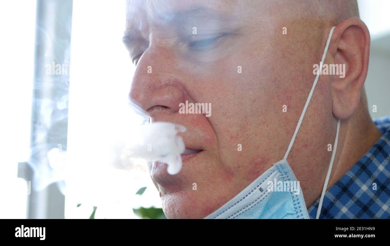 Image avec un homme qui fume une cigarette en utilisant on Le visage un masque de protection contre l'infection virale Banque D'Images