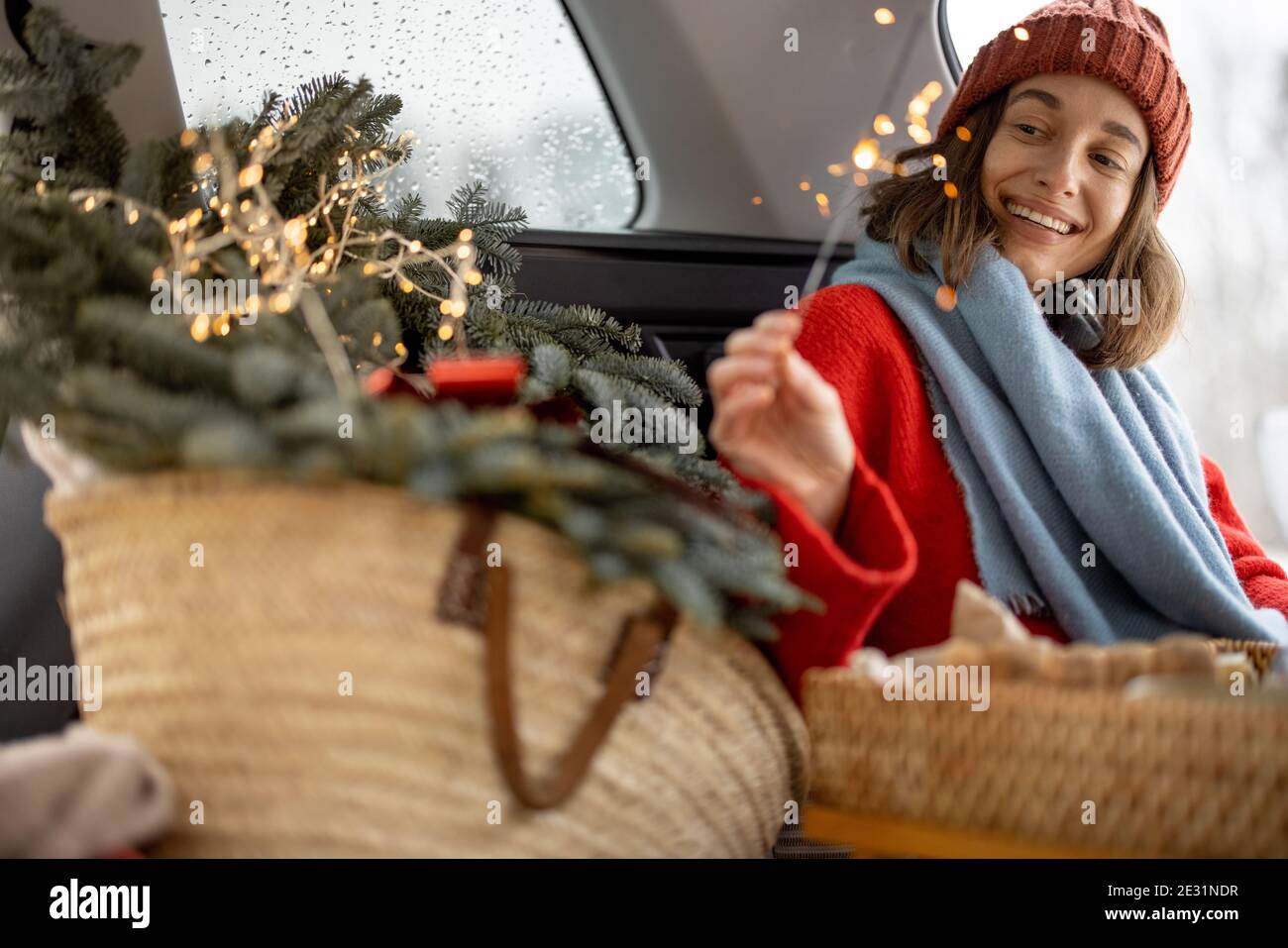 Femme souriant et regardant le sparkler en étant assise en voiture coffre Banque D'Images