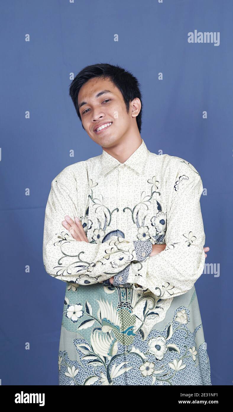 homme asiatique élégant avec des vêtements batik en studio isolé avec arrière-plan bleu Banque D'Images