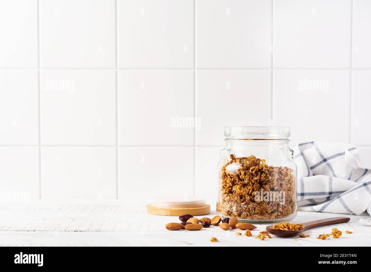 Faire une avoine de granola avec des noix et des fruits secs pour préparer un petit déjeuner sain sur une table lumineuse de cuisine. Style scandinave blanc. Mise au point sélective. Banque D'Images
