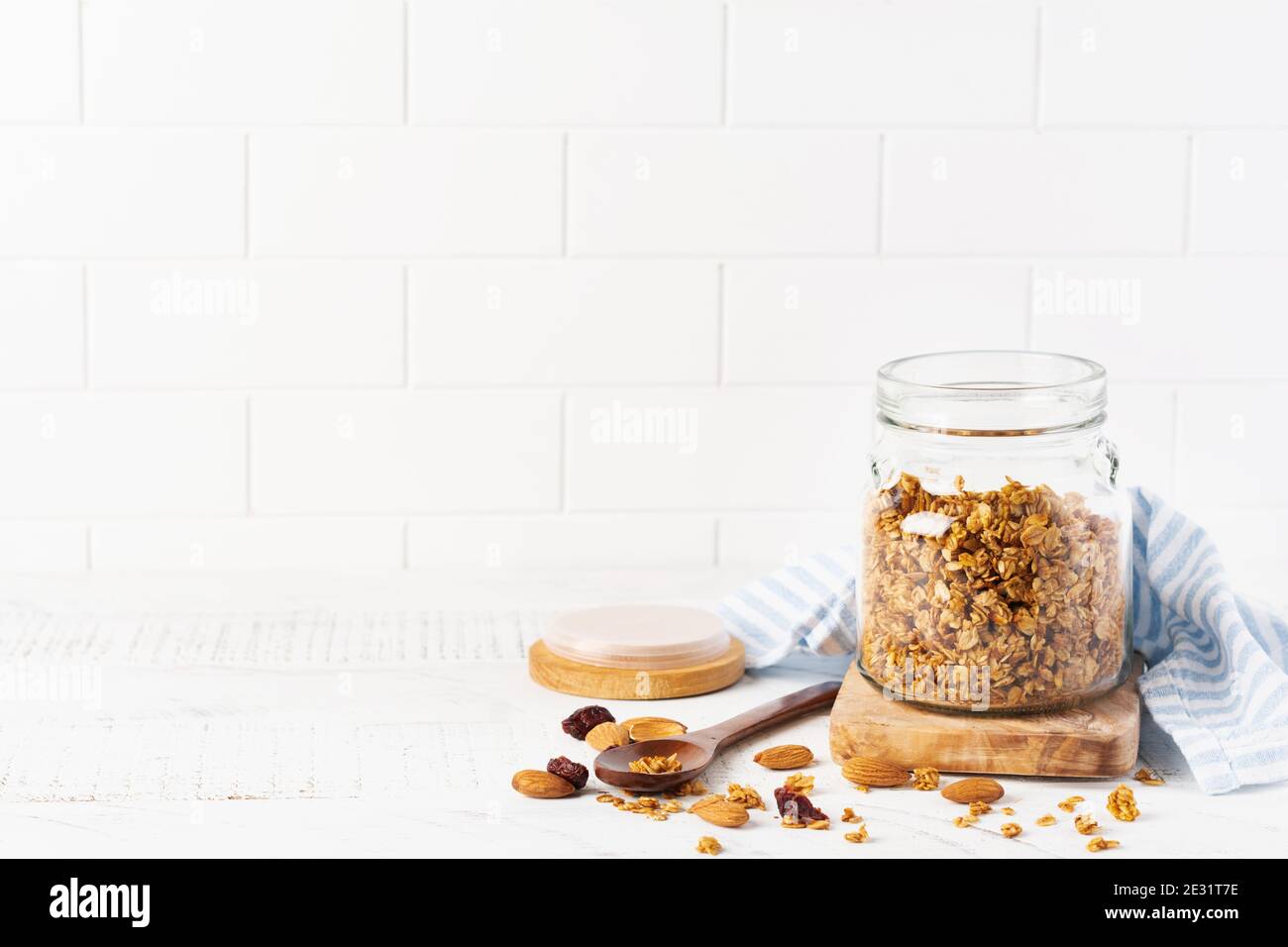 Faire une avoine de granola avec des noix et des fruits secs pour préparer un petit déjeuner sain sur une table lumineuse de cuisine. Style scandinave blanc. Mise au point sélective. Banque D'Images