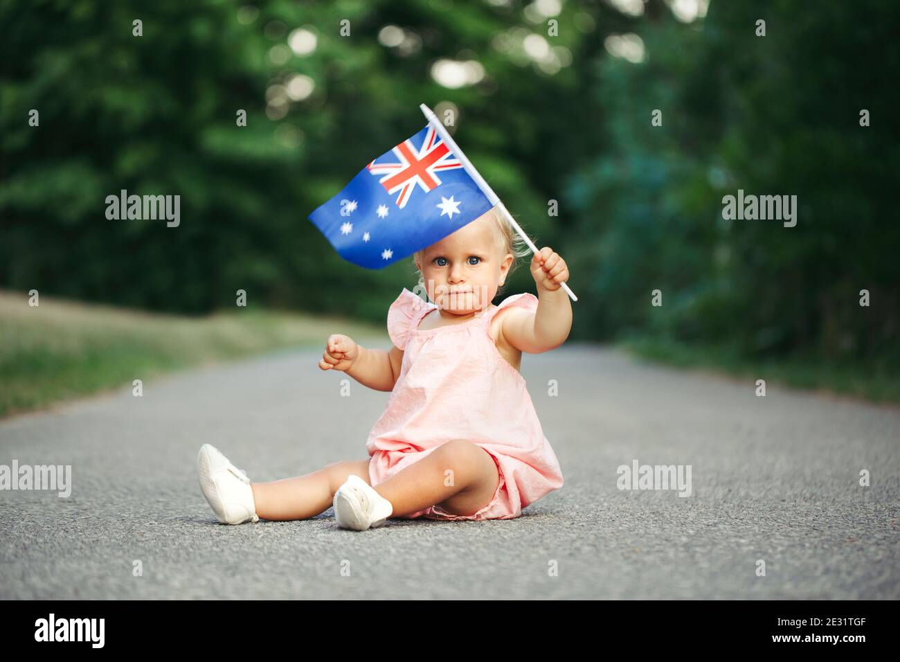 Adorable adorable petite fille caucasienne portant le drapeau australien.  Enfant souriant assis sur la rue dans le parc célébrant les vacances de  l'Australia Day. Célébration Photo Stock - Alamy