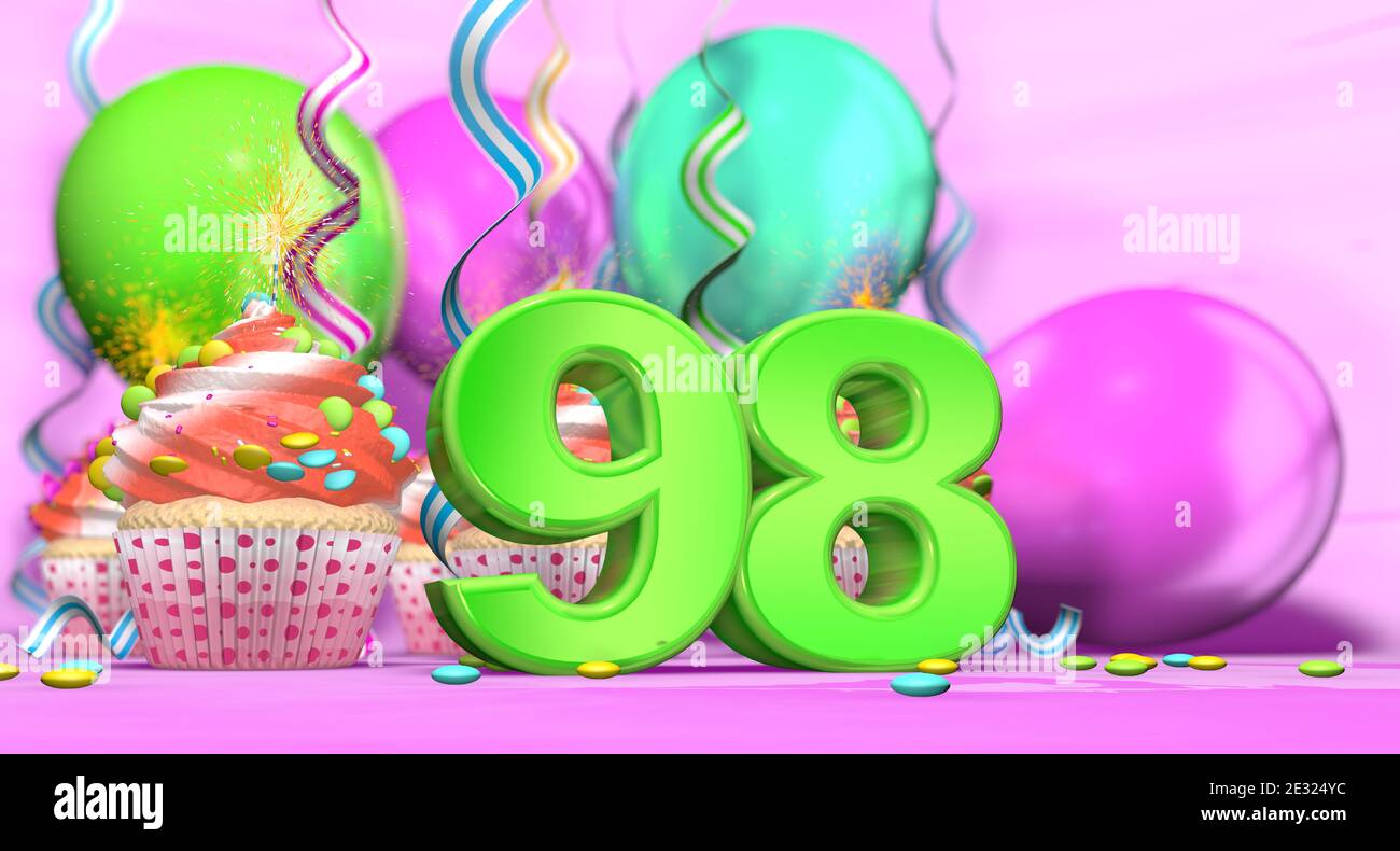 Gâteau d'anniversaire avec bougie parfumée avec le numéro 98 grand en vert avec des petits gâteaux à la crème rouge et au chocolat jetons et ballons sur th Banque D'Images