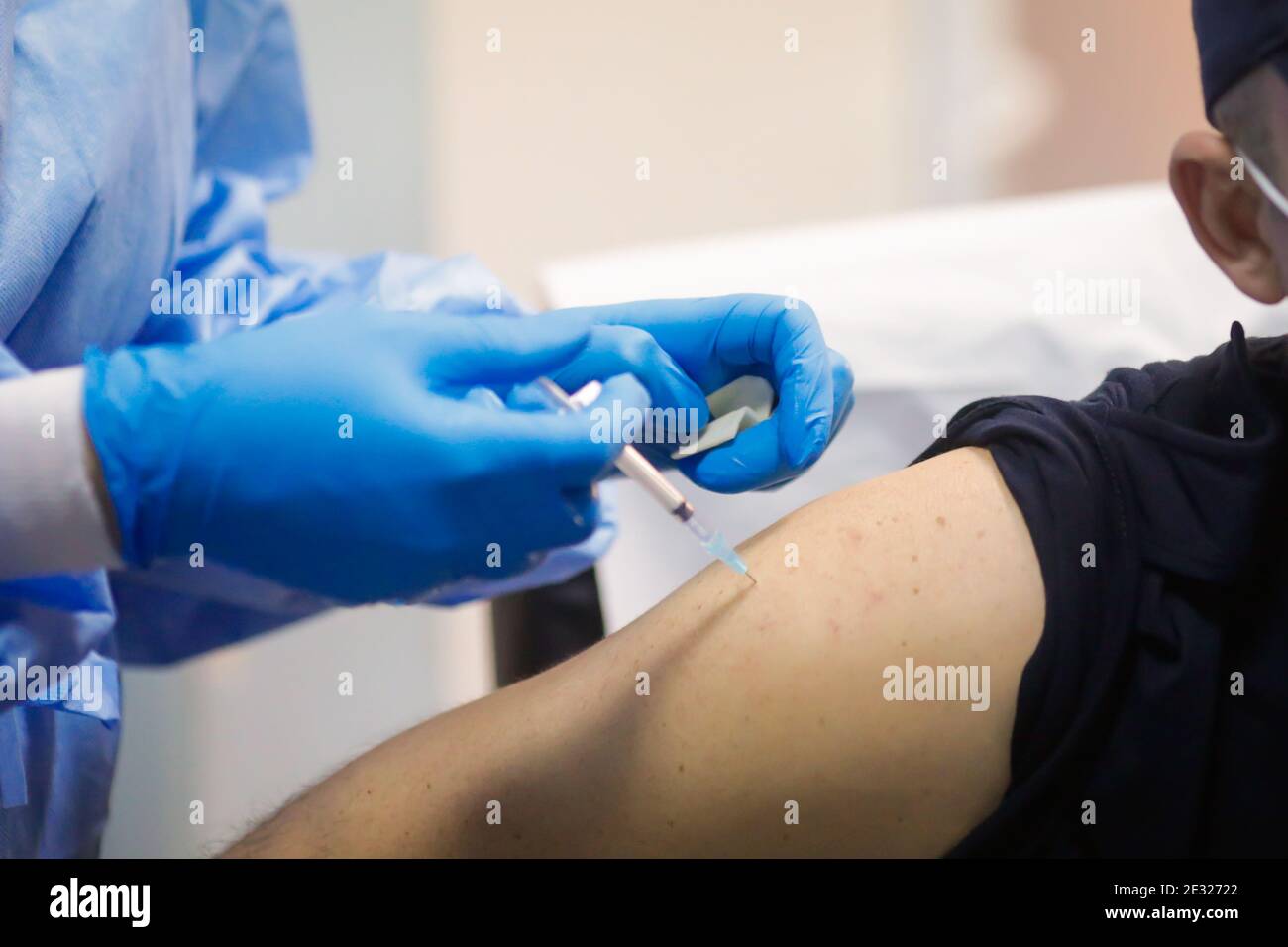 Détails sur un homme qui reçoit une injection intramusculaire avec le vaccin contre le SRAS-COV-2 dans un hôpital par un travailleur médical. Banque D'Images
