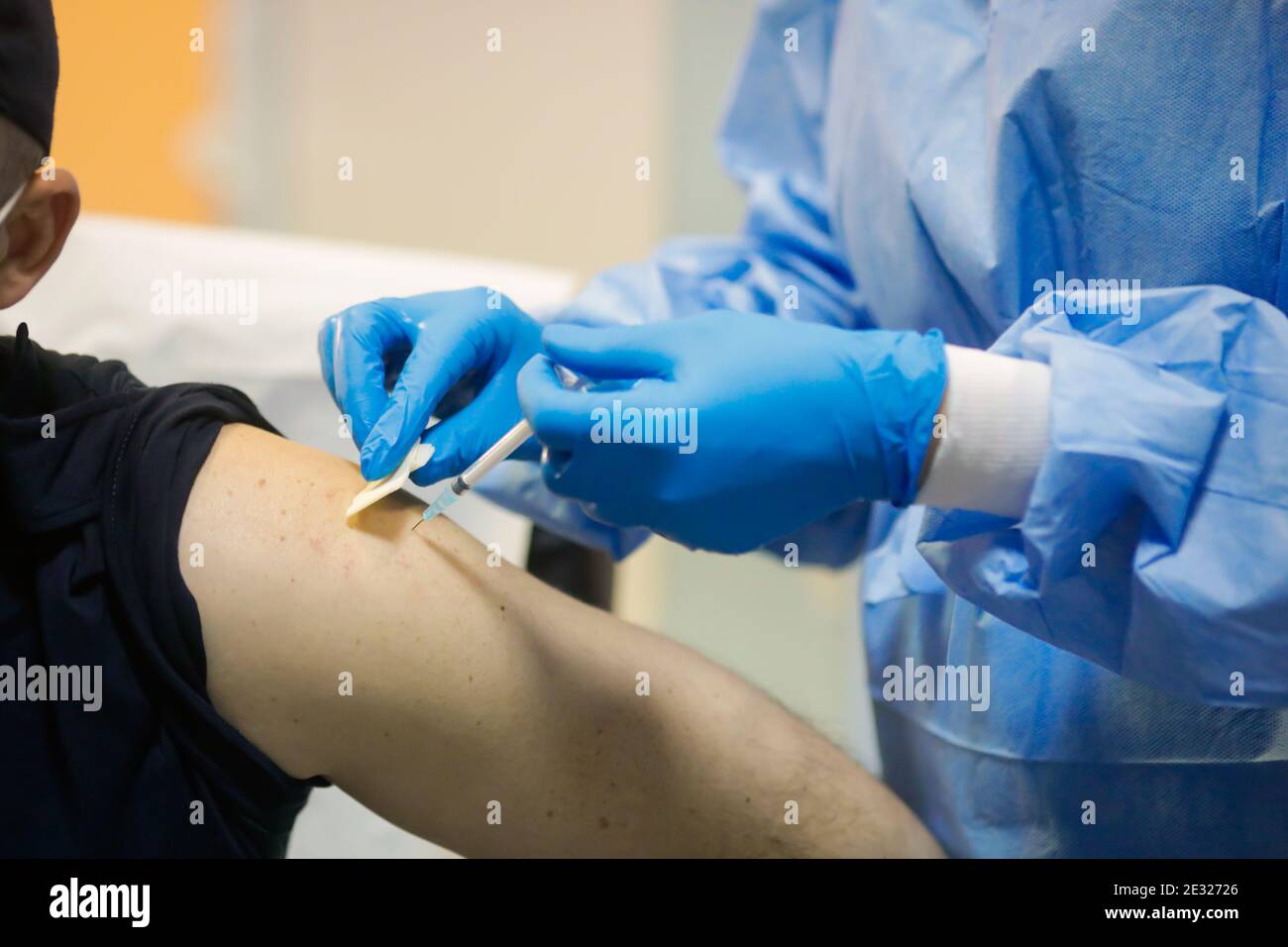 Détails sur un homme qui reçoit une injection intramusculaire avec le vaccin contre le SRAS-COV-2 dans un hôpital par un travailleur médical. Banque D'Images