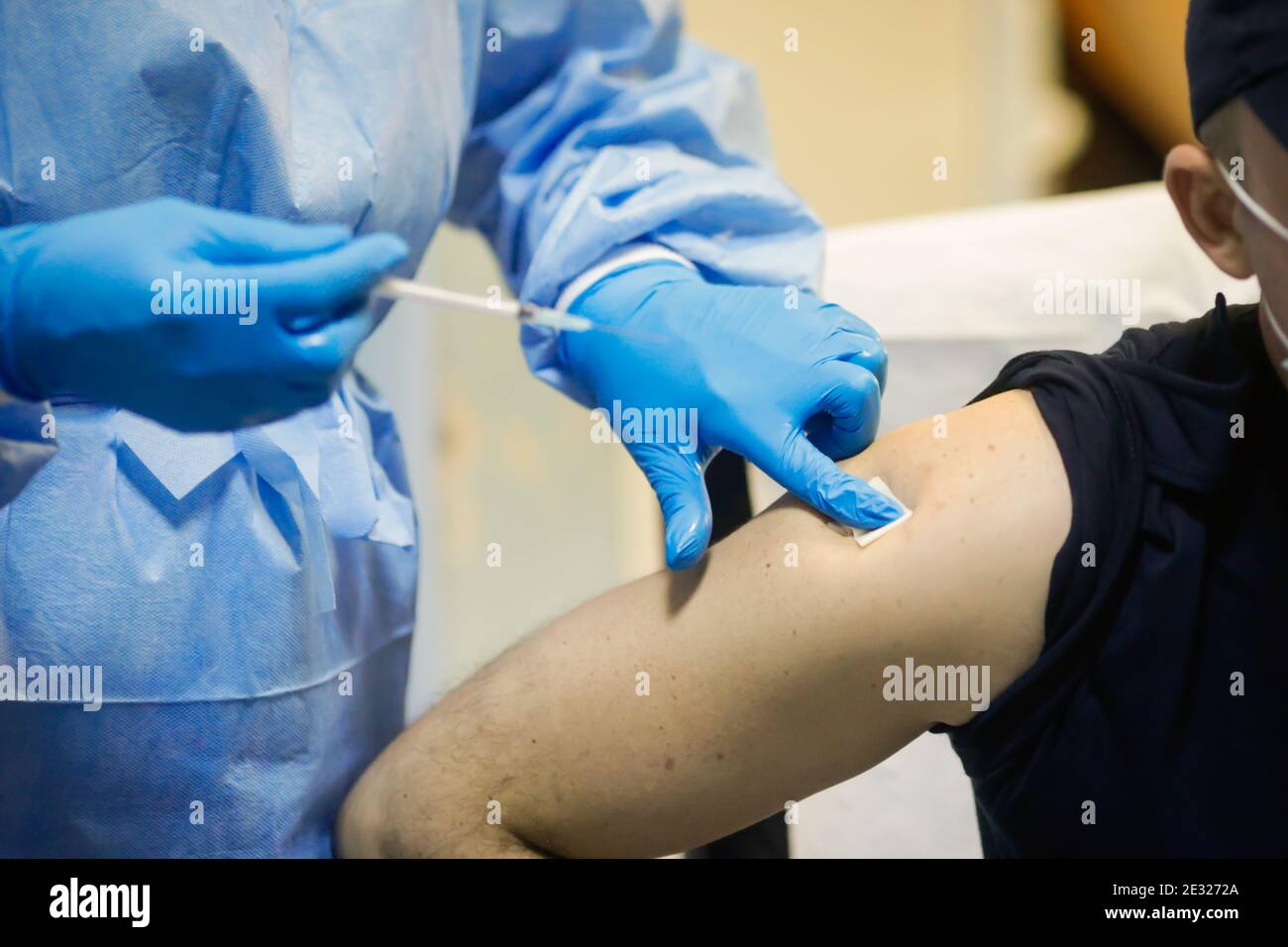 Détails sur un homme qui reçoit une injection intramusculaire avec le vaccin contre le SRAS-COV-2 dans un hôpital par un travailleur médical. Banque D'Images