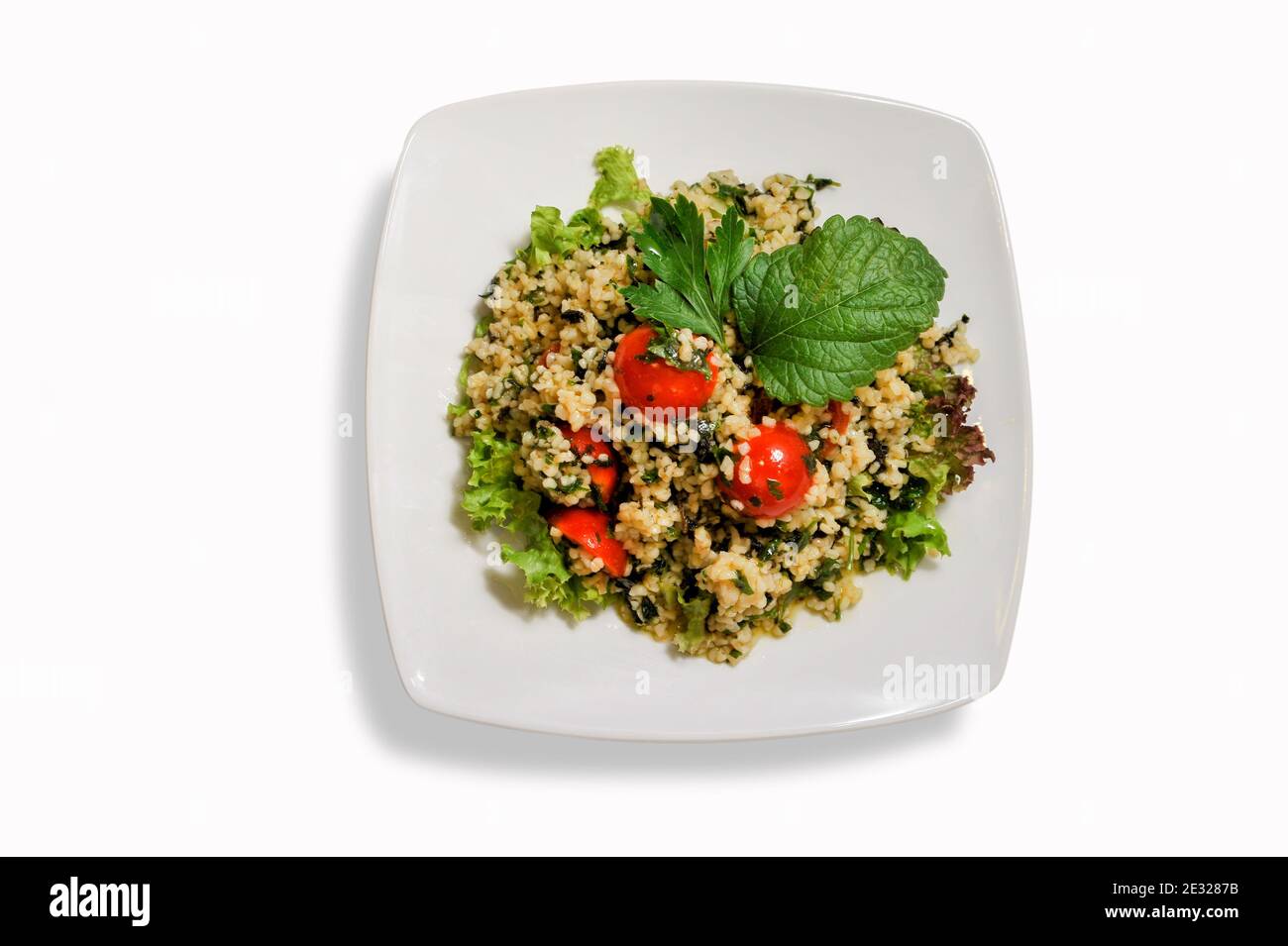 Tabouleh de couscous - salade et légumes couscous dans une assiette blanche isolée sur fond blanc vue du dessus. Copier l'espace. Banque D'Images