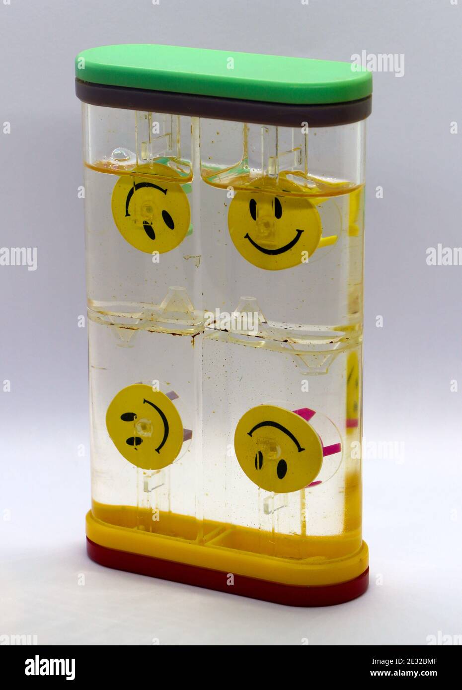 Photo d'un jouet visage smiley pour enfants fonctionnant par gravité alimenté par l'eau avec 4 visages sur des roues mobiles dans 4 cellules sur un fond blanc Banque D'Images