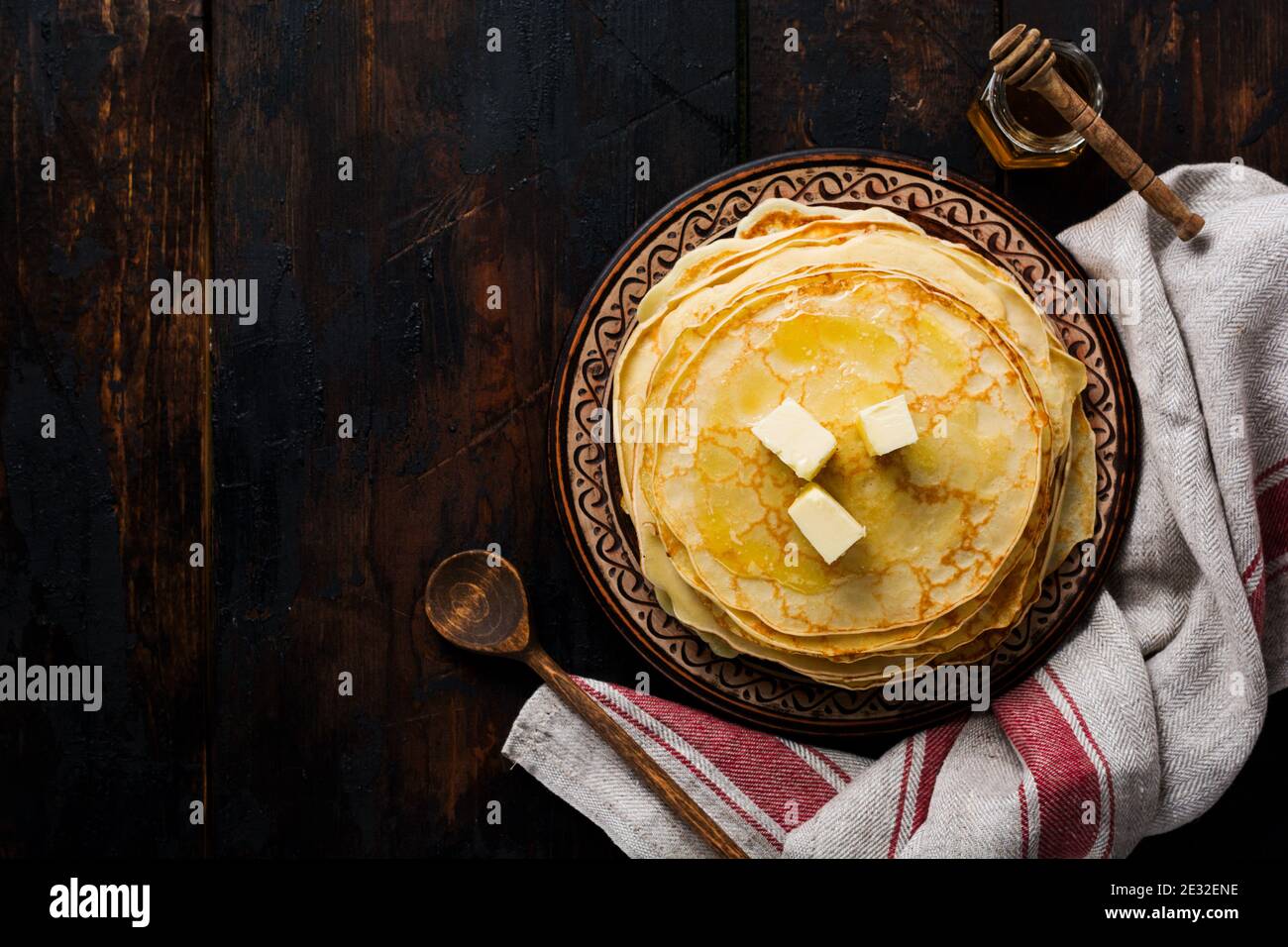 Pile de crêpes fines faites maison avec des morceaux de beurre, de lait et de miel sur l'ancienne plaque de céramique rustique. Vue de dessus Banque D'Images