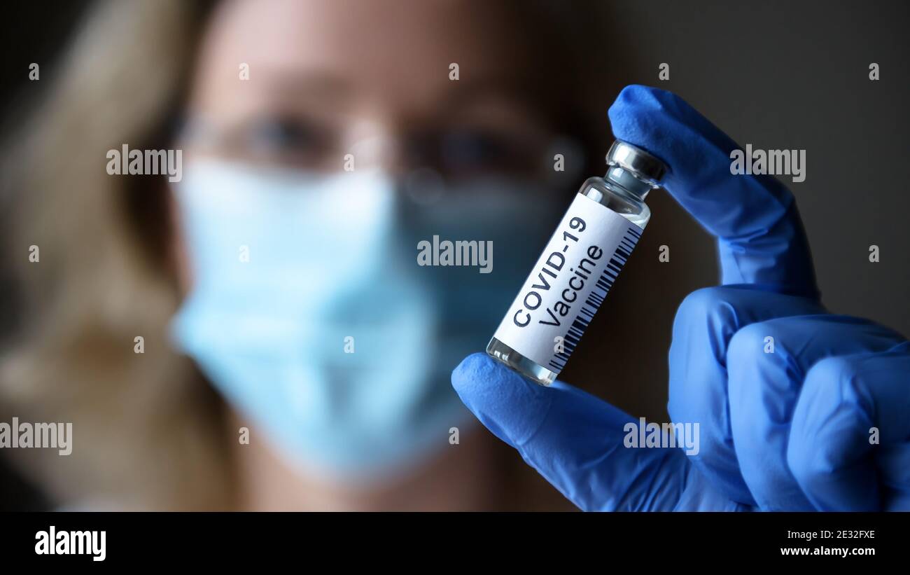 Le vaccin COVID-19 en gros plan, une femme médecin et une bouteille avec un médicament pour la guérison du coronavirus en laboratoire. Concept de traitement du virus corona Banque D'Images