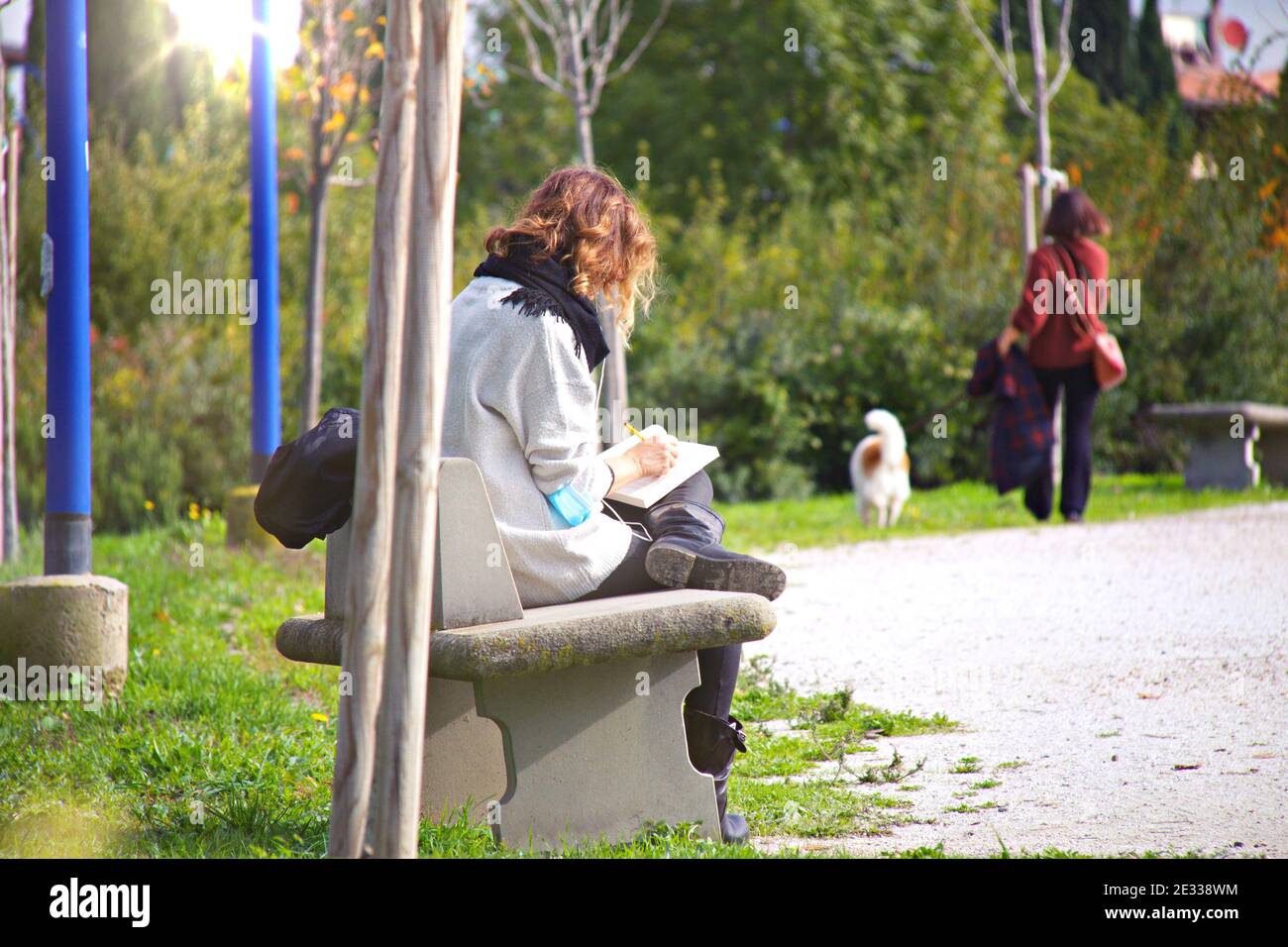 Prise de vue en début de matinée de 'la nouvelle normalité' dans un parc public de Florence, personne lisant un livre gardant la distance et le masque, femme marchant avec le chien comme ba Banque D'Images