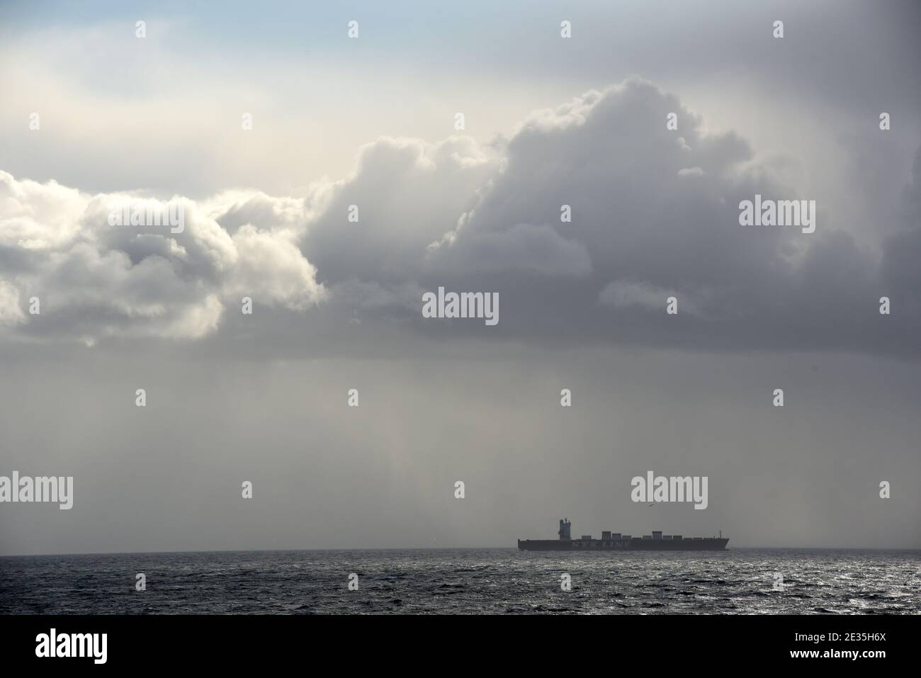 Les nuages flottent dans le ciel au-dessus de la tête, tandis qu'un cargo transporte des conteneurs d'expédition sur l'océan au large de la côte de l'île de Vancouver, en Colombie-Britannique, au Canada Banque D'Images