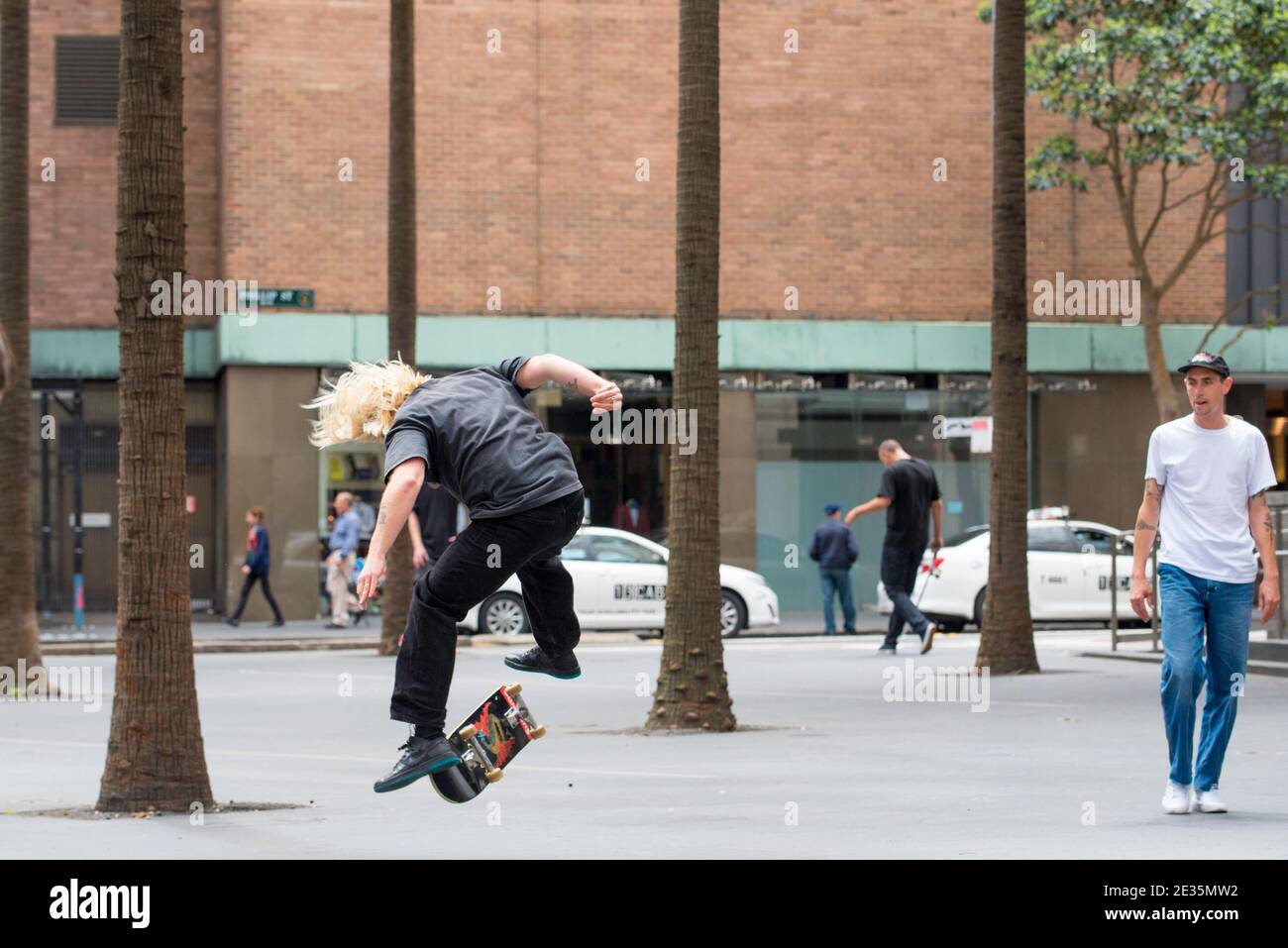 Un jeune coureur de skateboard australien réalise un flip and shove IT trick dans le centre de Sydney, en Australie Banque D'Images