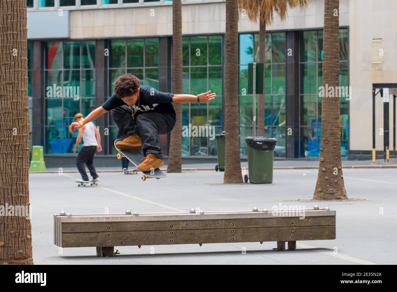 Un jeune coureur de skateboard australien effectue un flip ou une ollie sur un banc de bois dans le centre de Sydney, en Australie Banque D'Images