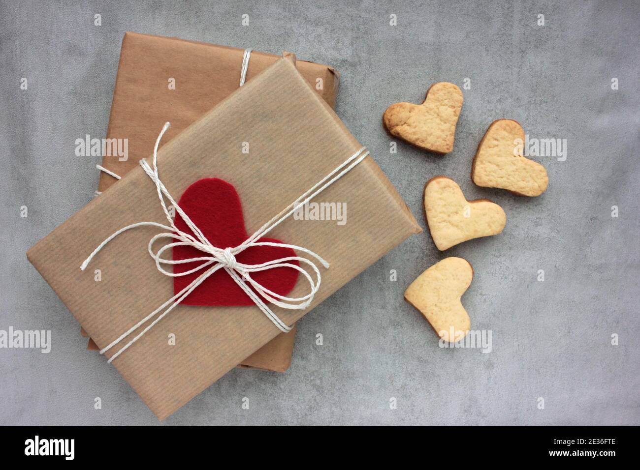 Boîte cadeau avec biscuits en forme de coeur et de coeur sur fond de béton  gris.Emballage de cadeau en papier kraft et décoré de coeur en feutre.Vue de  dessus Photo Stock -