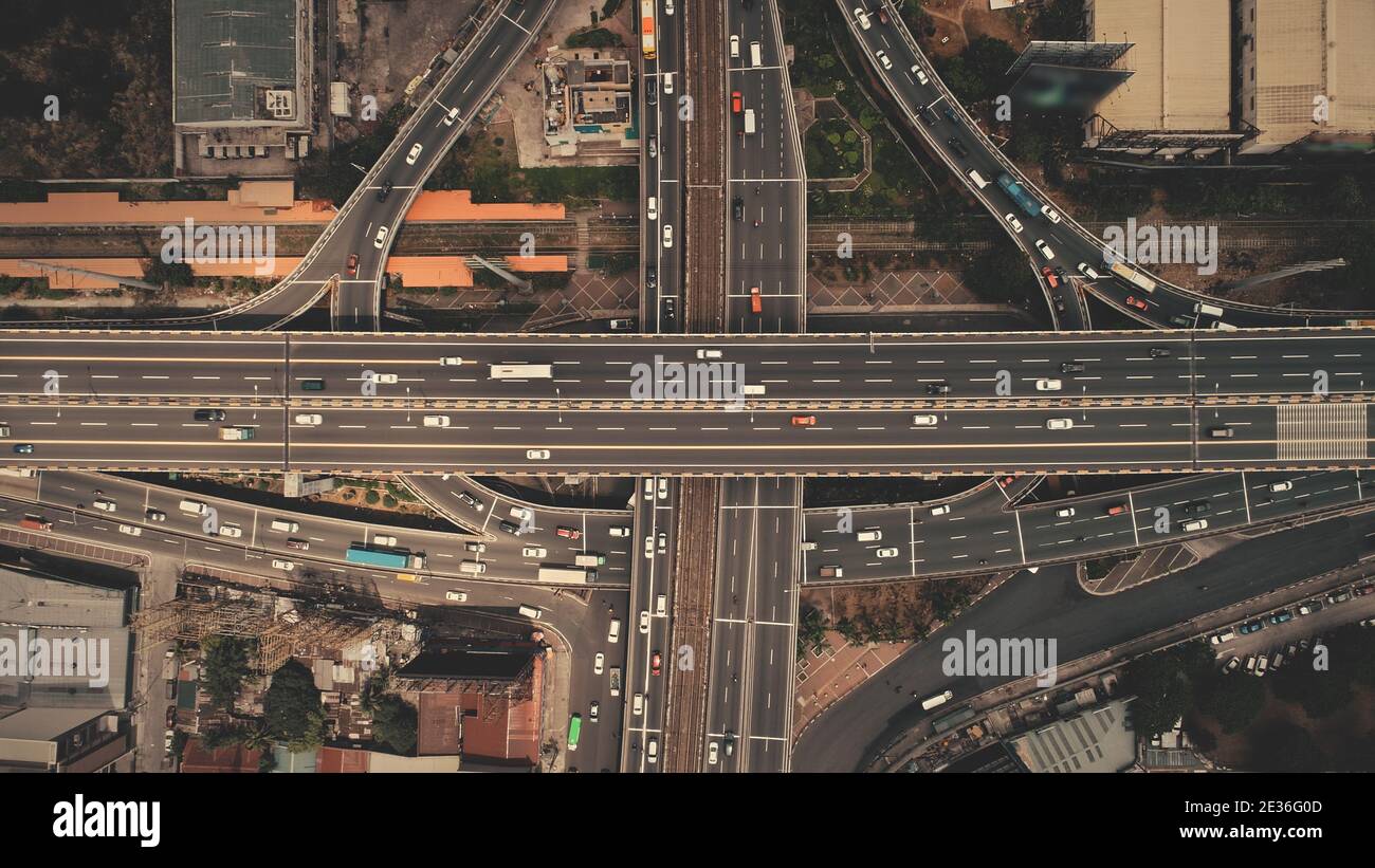 Traversez le sommet de l'autoroute vers le bas à la capitale des Philippines vue aérienne du paysage urbain. Des voitures, des bus, des fourgonnettes et des camions circulent sur la route de la ville de Manille. Scène urbaine avec des bâtiments, gratte-ciel, chalets au bord de la route Banque D'Images