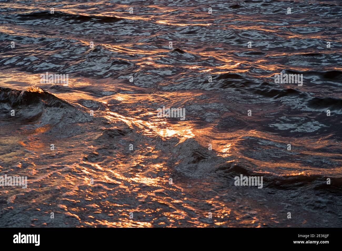 Reflet de la lumière du coucher du soleil dans la surface des petites vagues Banque D'Images