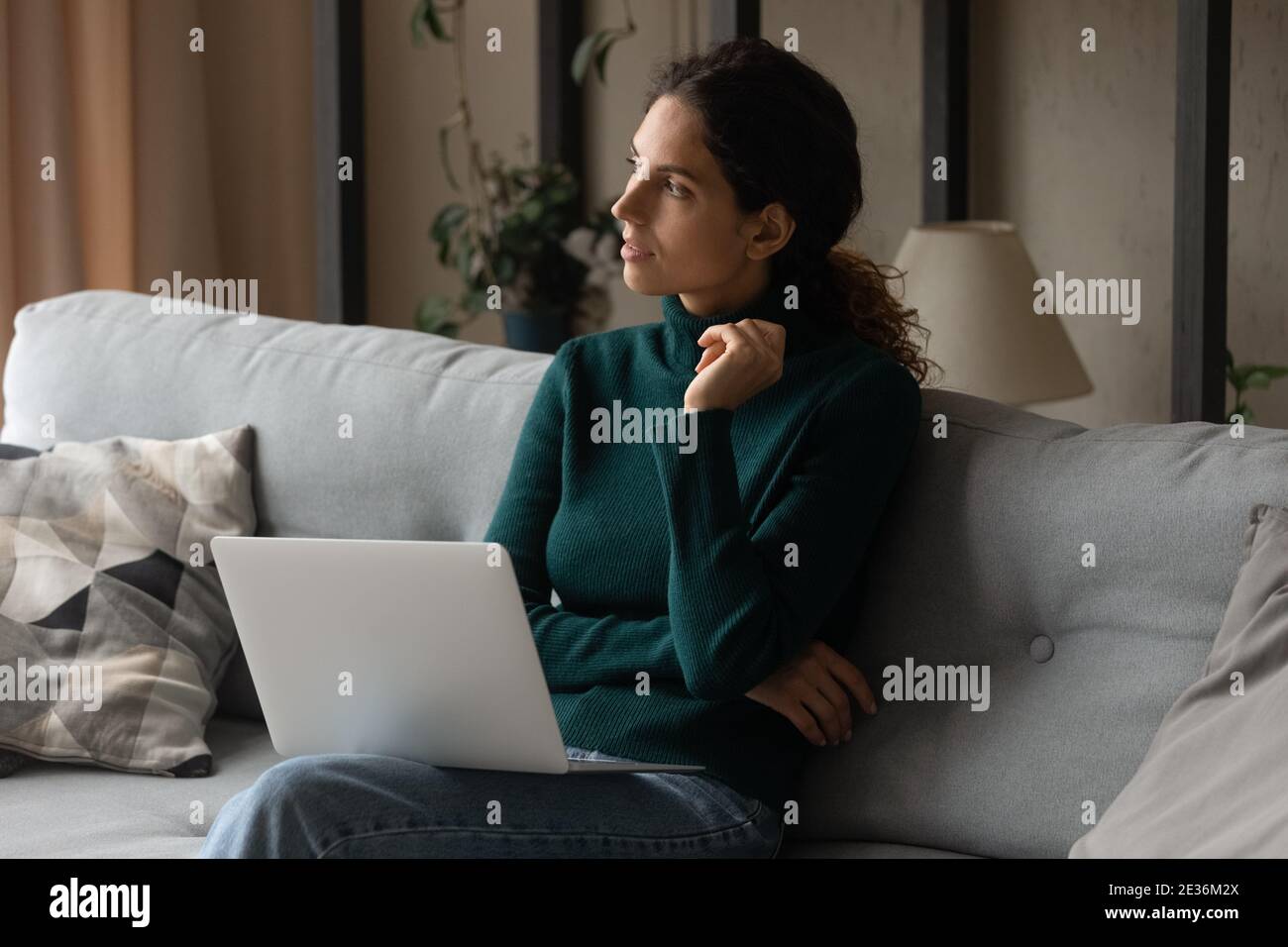 Une jeune femme pensive travaille sur un ordinateur portable Banque D'Images
