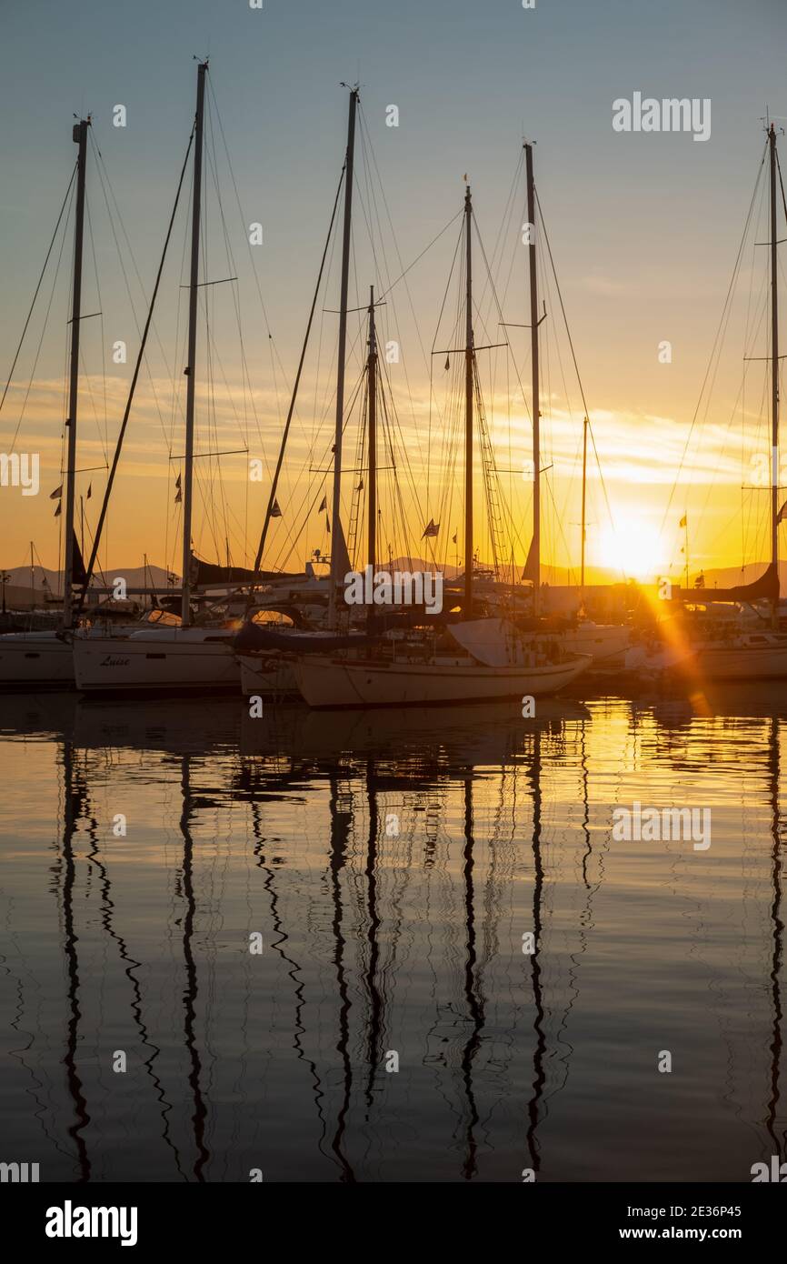 Des bateaux à voile amarrés au coucher du soleil dans les eaux du port de l'île Saronique d'Aegina ( Egina ) près d'Athènes, Golfe Saronique, Grèce Banque D'Images