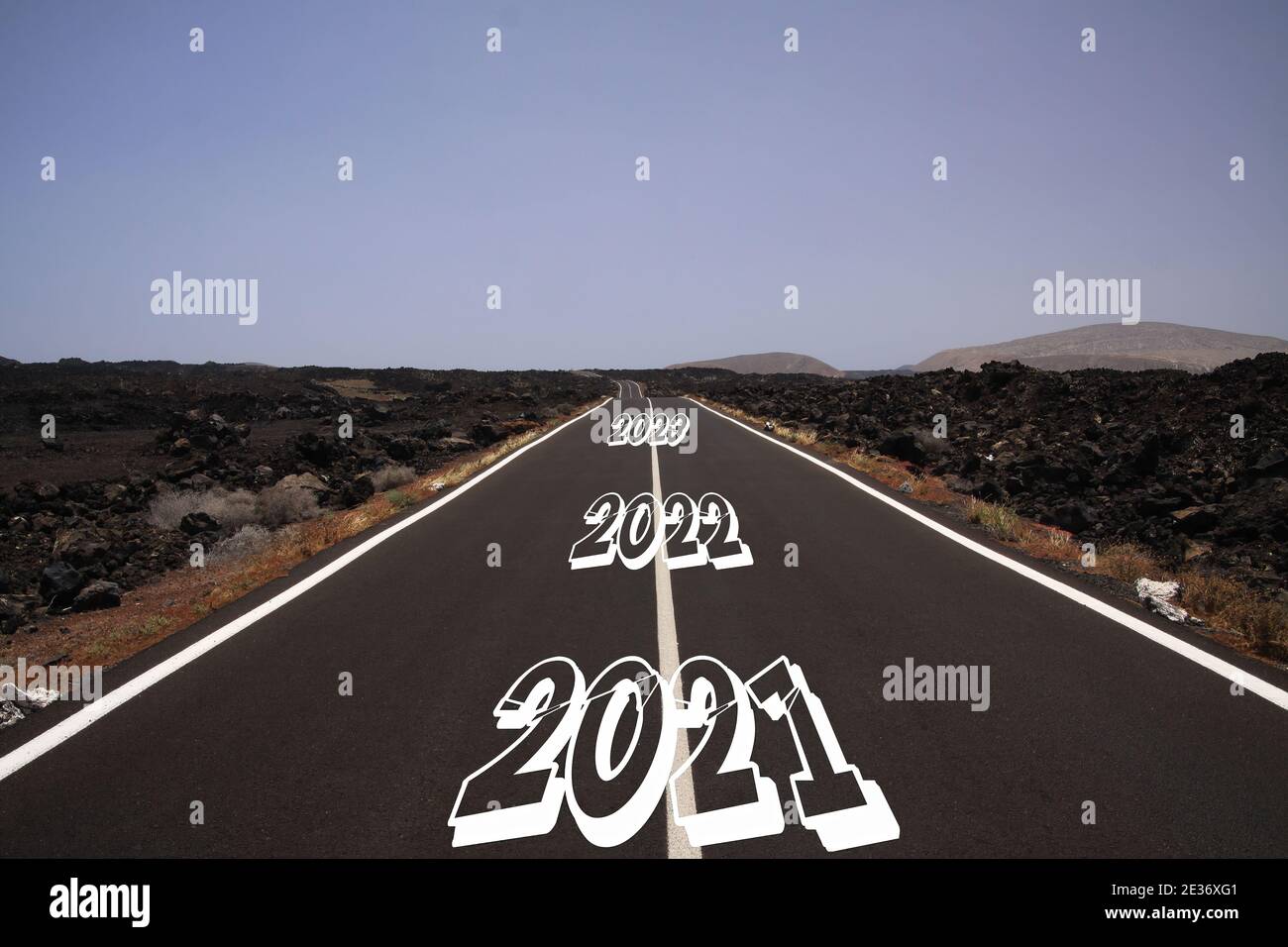 Long dur rocailleux succès concept: Vue sur la route d'asphalte sans fin à travers le paysage volcanique aride sec avec des nombres d'années 2021, 2022, 2023 Banque D'Images
