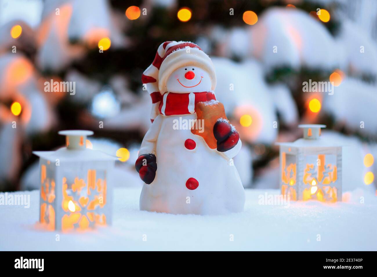 Décoration de Noël extérieure avec bonhomme de neige, lanternes, neige et lumières de fées sur l'arbre de Noël Banque D'Images