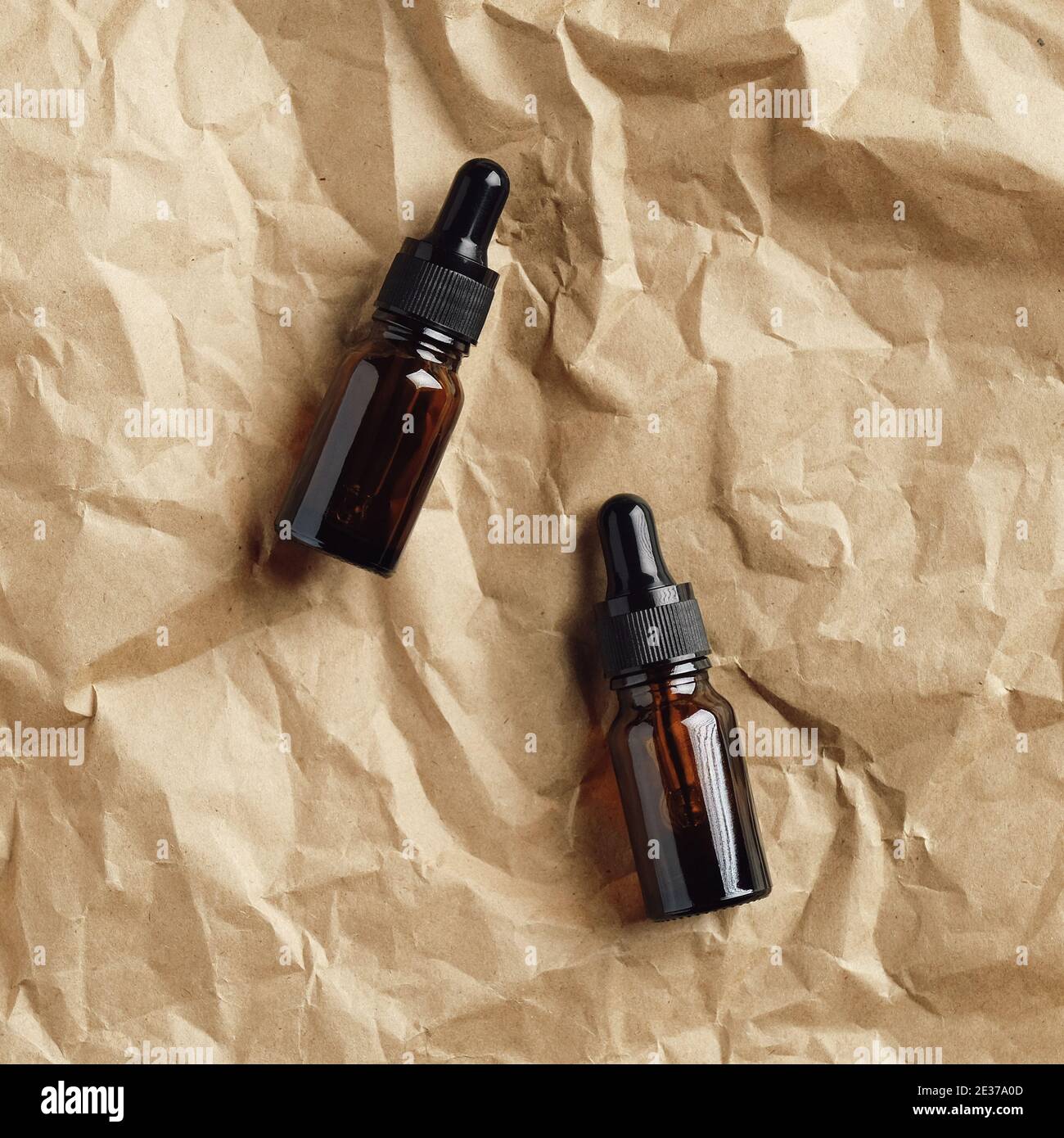 Flacons compte-gouttes en verre ambré sur papier kraft. Vue de dessus des sérums naturels. Banque D'Images