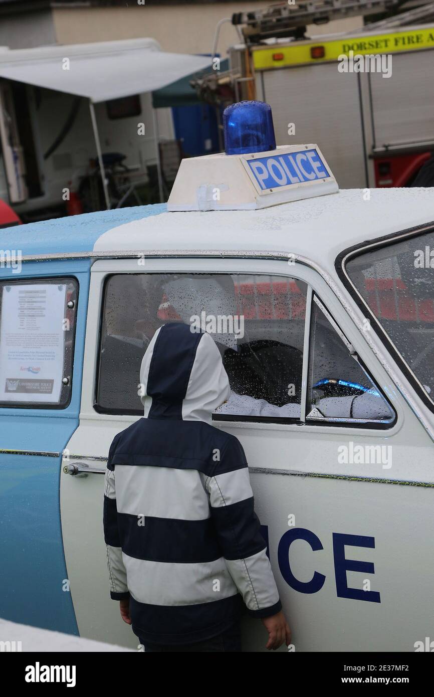 Spectacle aérien international écossais . Dimanche 4 sept 2017 .Low Green, Ayr, Ayrshire, Écosse, Royaume-Uni . Un après-midi humide au salon de l'air. Un petit garçon à capuche noir et blanc regarde à travers la fenêtre d'une voiture de police vintage des années 1960 Ford Anglia Banque D'Images