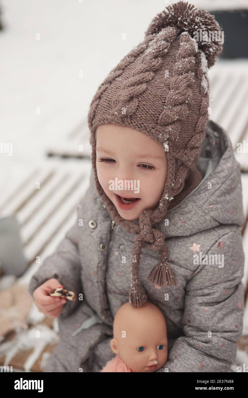 Jolie petite fille jouant avec une poupée dehors en hiver Banque D'Images