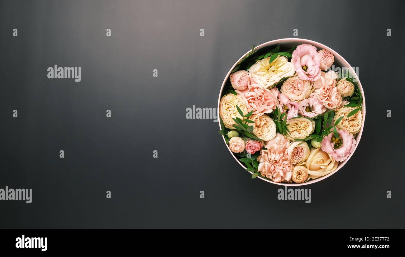 Une fleur élégante et délicate dans une boîte ronde à chapeau sur fond rose avec espace de copie. Boîte cadeau pour le 8 mars, Journée internationale de la femme Banque D'Images