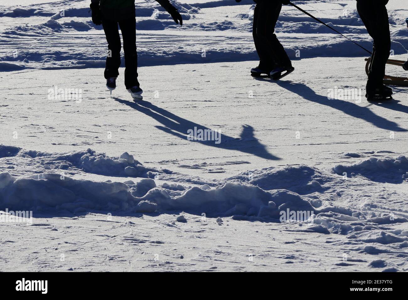 Patineurs de glace sur un lac gelé en Bavière contre le lumière du soleil Banque D'Images