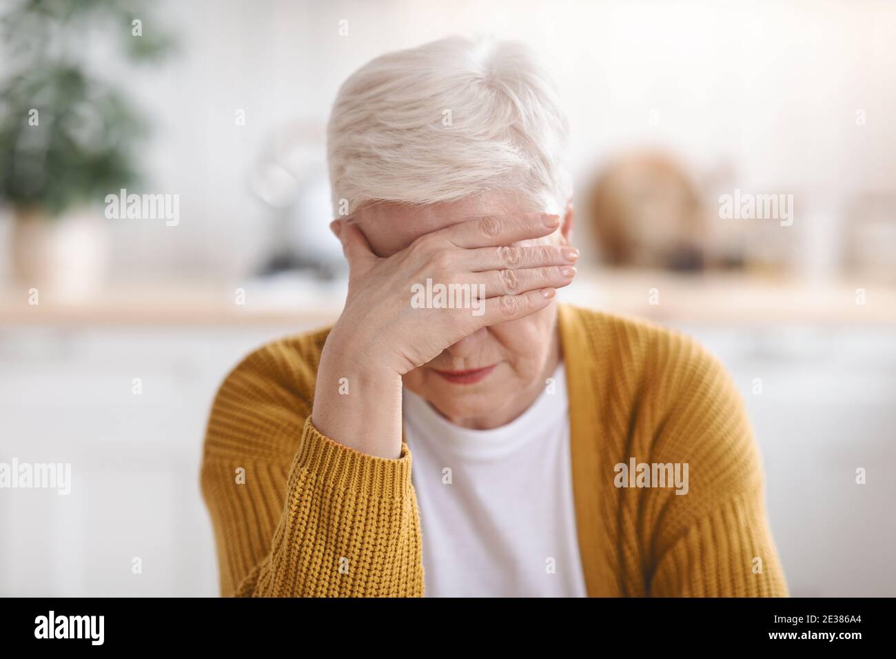 Femme âgée souffrant de migraine, cuisine intérieure Banque D'Images