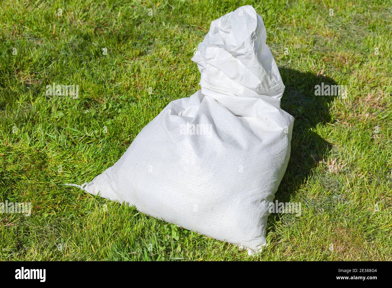 Le sac en polypropylène blanc repose sur l'herbe verte au soleil jour Banque D'Images