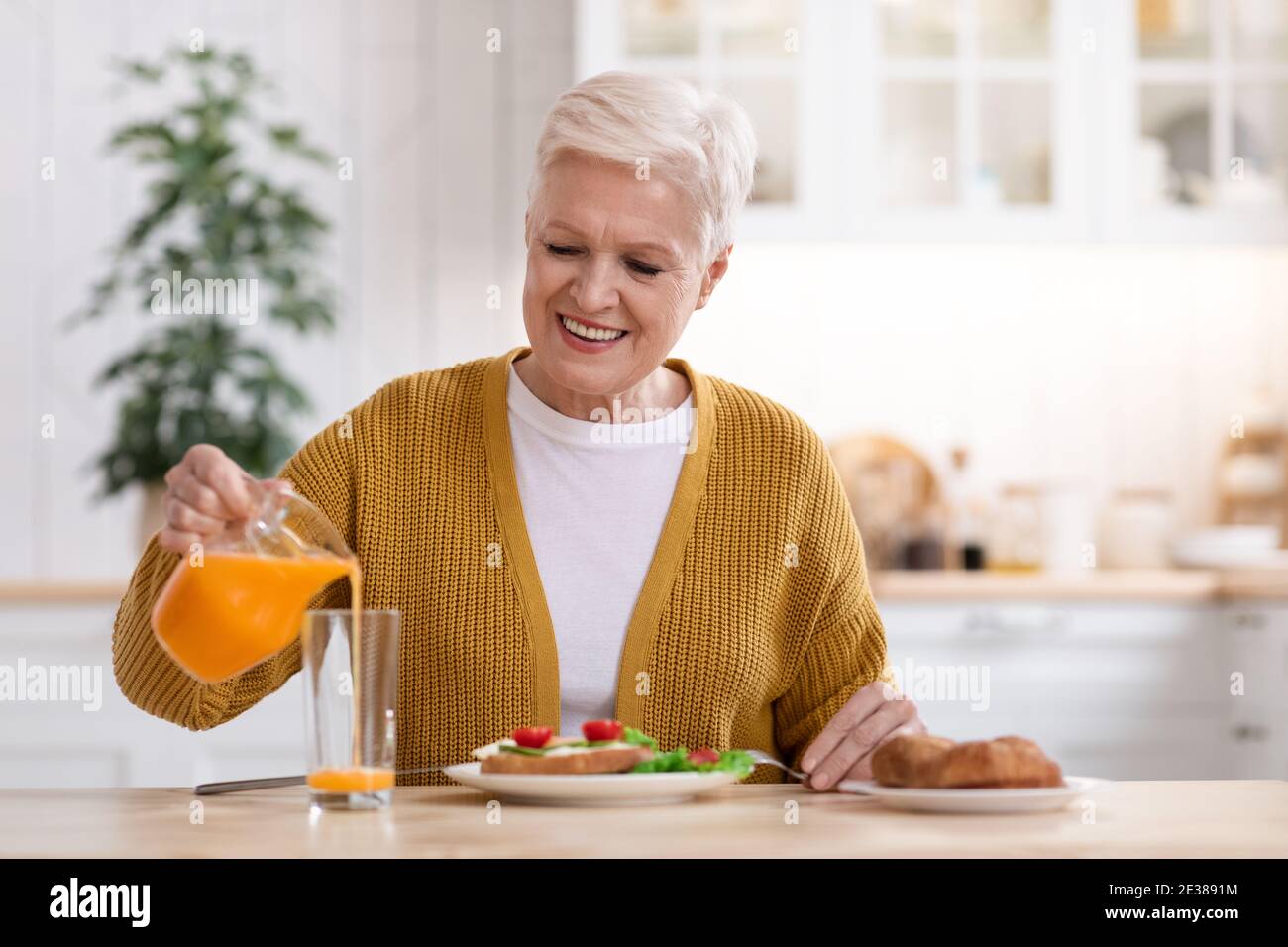 Femme âgée joyeuse ayant un déjeuner sain à la maison Banque D'Images
