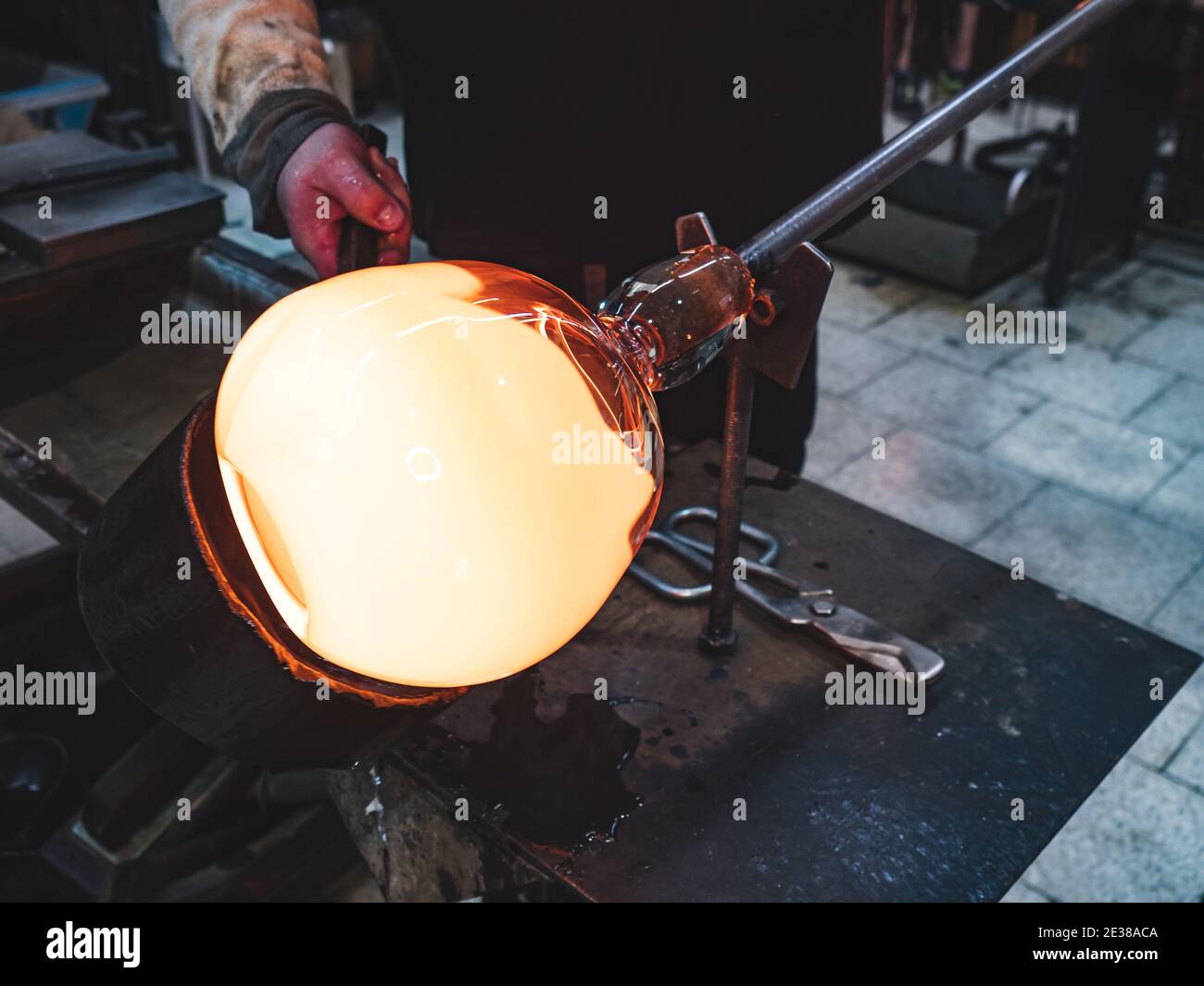 Souffleur de verre formant un morceau de verre chaud avec un outil en bois.  Le fer à frer traditionnel en verre travaille avec brûler et souffler une  pièce d'art. Goujon en verre