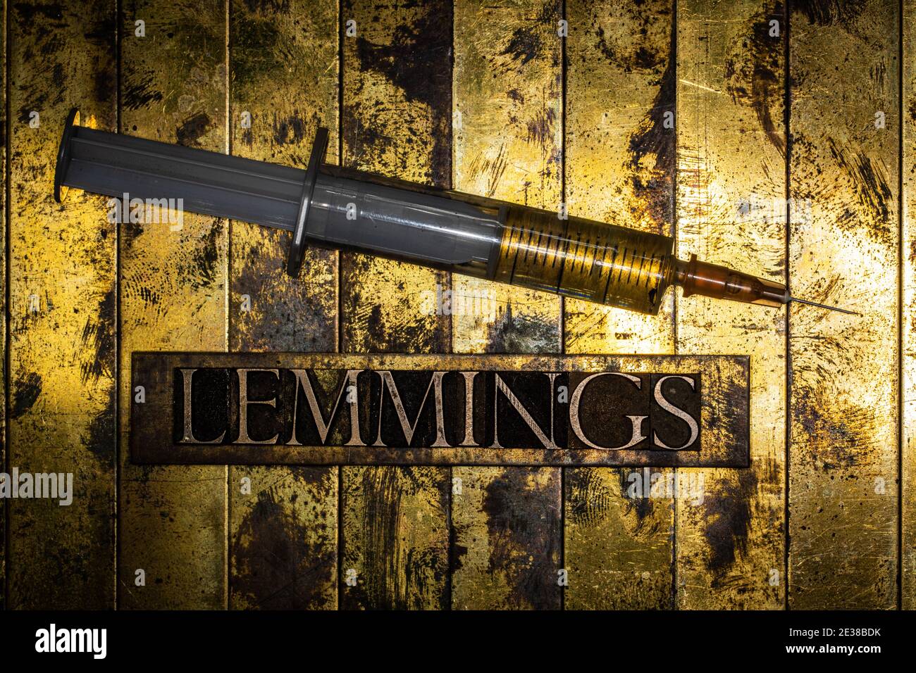 Texte des lemmings à côté de la seringue rempli de liquide sur le grunge fond texturé en cuivre et or Banque D'Images