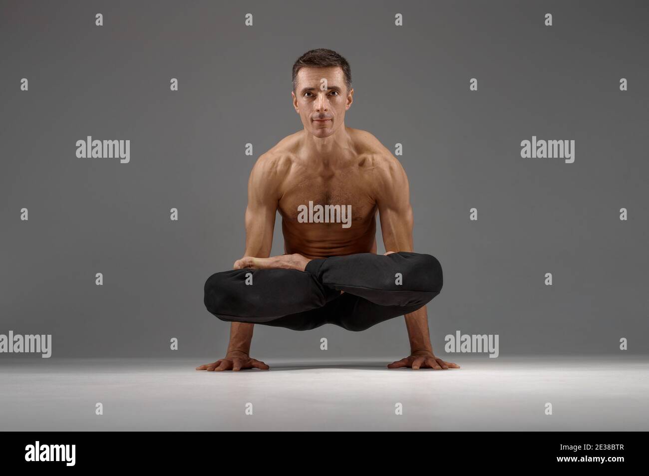 Le yoga masculin garde le balanc sur les mains dans la posture classique Banque D'Images