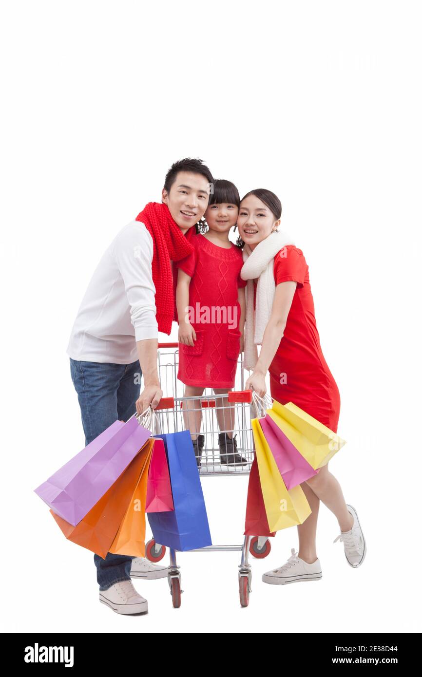 Portrait de la fille debout dans le chariot, avec les parents tenant le shopping sacs Banque D'Images