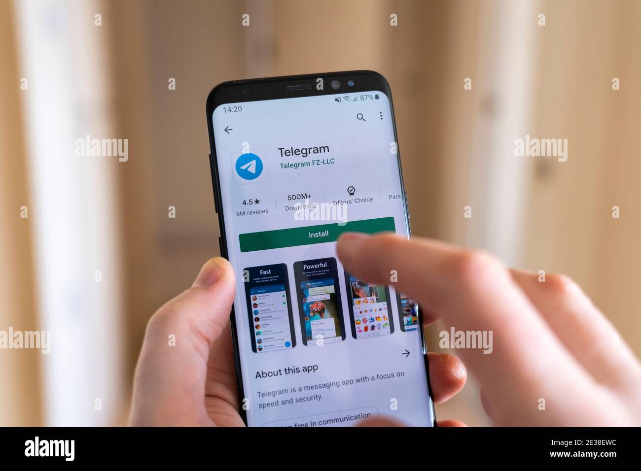 Une main tenant un smartphone avec un doigt en sélectionnant le Bouton installer sur le Google Play Store pour la vidéo Telegram, application de messagerie et de chat Banque D'Images