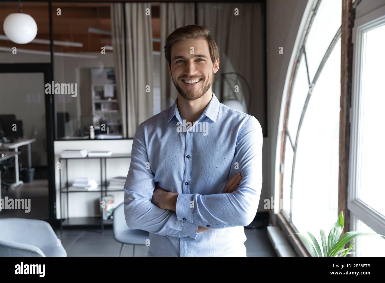 Portrait en tête souriant homme d'affaires réussi debout dans un bureau moderne Banque D'Images