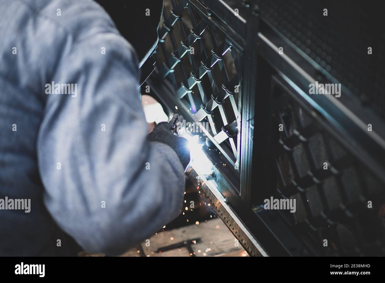 Le soudeur sourie les racks d'engrenages en acier à la porte avant de configurer l'opérateur de porte automatisé. Service professionnel d'installation et de maintenance de automatique Banque D'Images