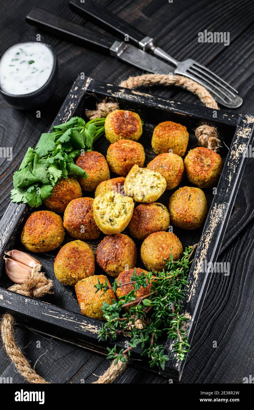 Boulettes de falafel de pois chiches rôtis avec sauce au yogourt à l'ail dans un plateau en bois fond noir. Vue de dessus Banque D'Images
