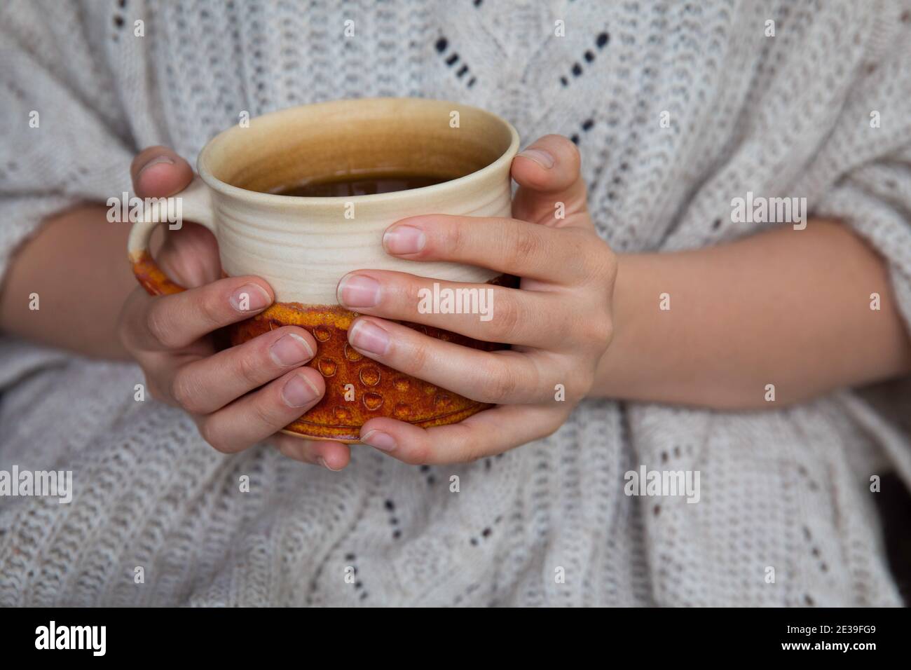 Jeune femme tenant une tasse de thé. Week-end d'automne ou d'hiver moody. Journée paresseuse, quarantaine, séjour à la maison, scène chaleureuse, concept d'hygge. Banque D'Images
