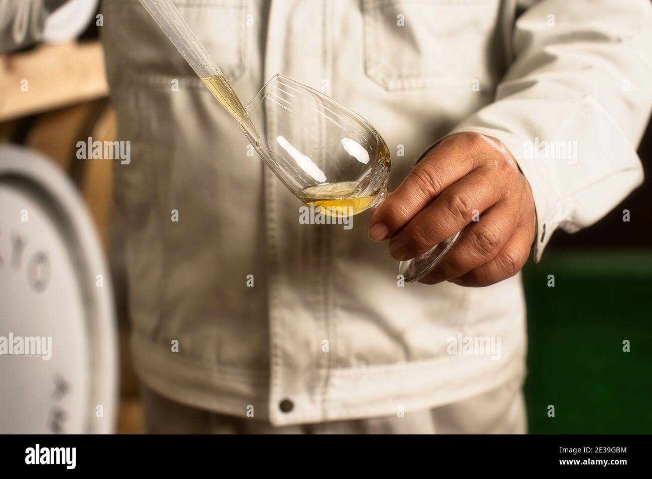 Maître distillateur prenant un échantillon d'un baril de chêne avec Une pipette et tenant le verre à Hatozaki Whisky in Japon Banque D'Images