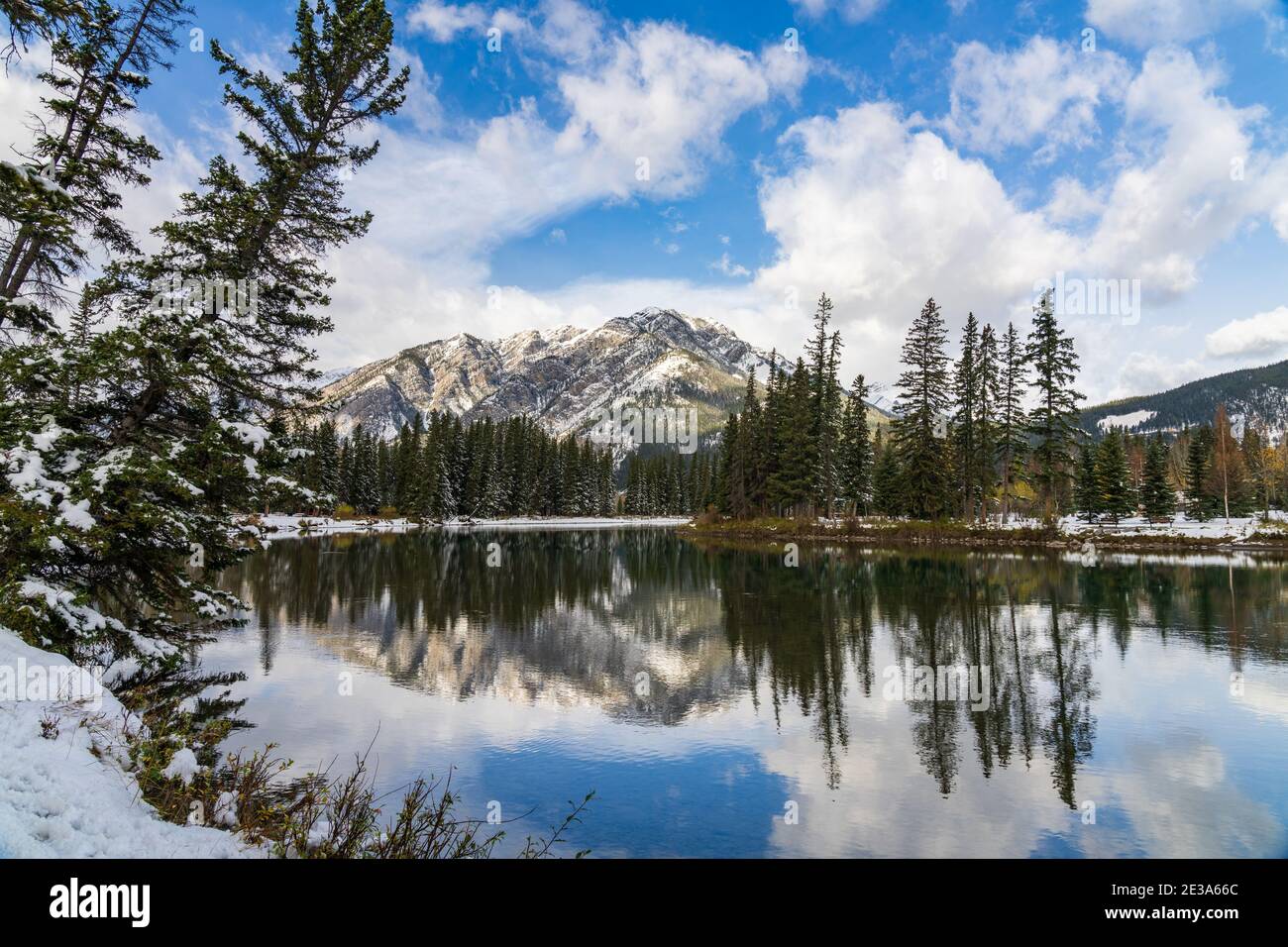 Parc national Banff magnifique paysage naturel en hiver ensoleillé. Mont Norquay avec ciel bleu, nuages blancs réfléchis sur la rivière Bow comme un miroir Banque D'Images