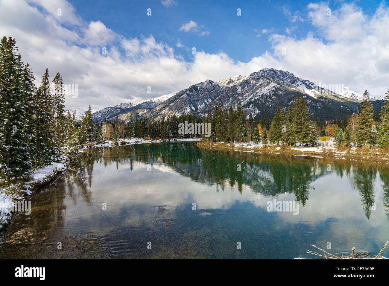 Parc national Banff magnifique paysage naturel en hiver ensoleillé. Mont Norquay avec ciel bleu, nuages blancs réfléchis sur la rivière Bow comme un miroir Banque D'Images