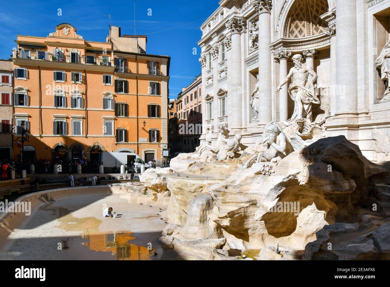 Un ouvrier s'accrousse comme ils font l'entretien et la restauration dans une fontaine de Trevi vide à Rome, Italie Banque D'Images