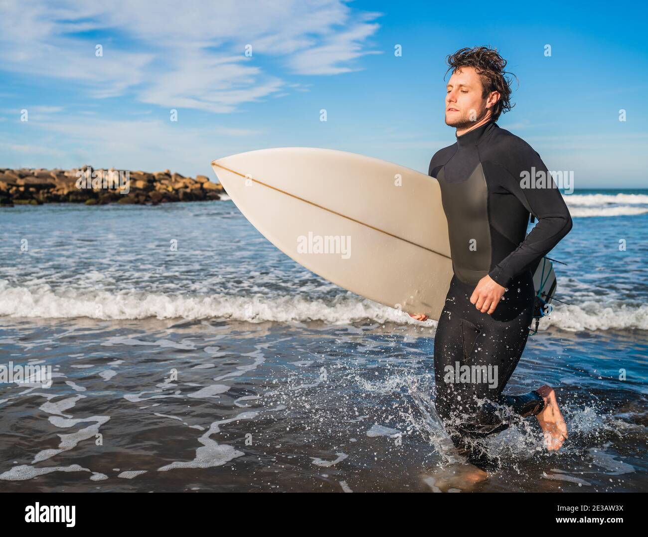 Surfeur laissant l'eau avec planche de surf sous son bras. Banque D'Images