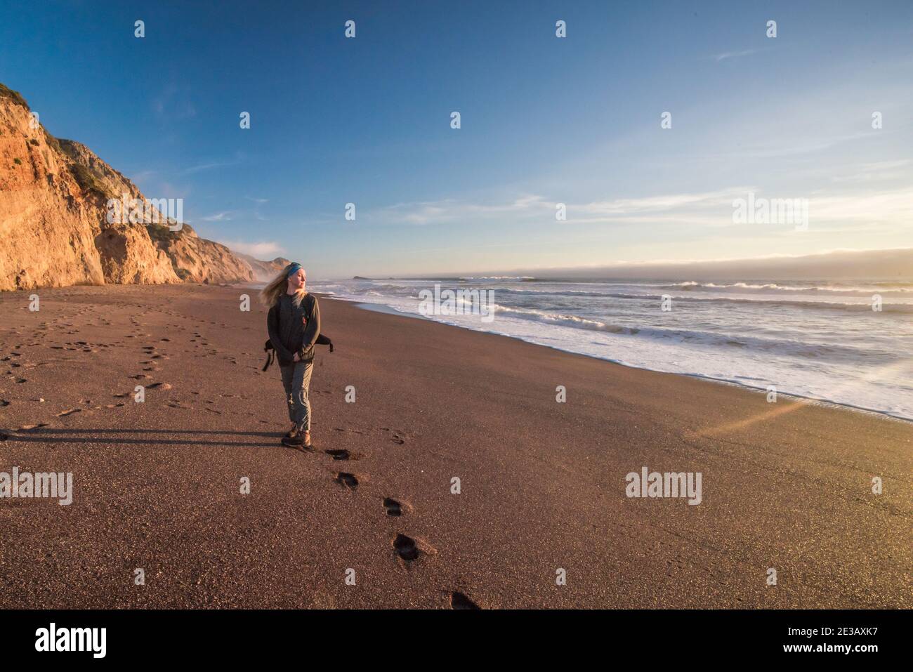 Une femme seule se tient sur une plage vide dans le littoral national de point Reyes, en Californie, en regardant l'océan Pacifique. Banque D'Images